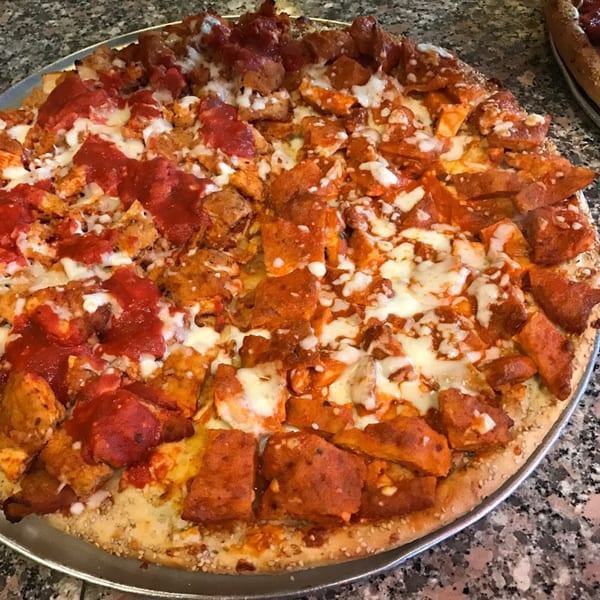 A large pizza from Touch of Italy, half with red sauce and half with buffalo chicken.