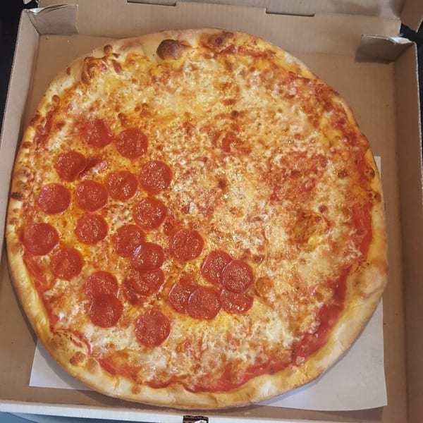 A large, round pizza with half cheese and half pepperoni, in a cardboard box.
