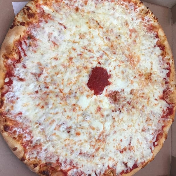A large, round cheese pizza with a small dollop of red sauce in the center.