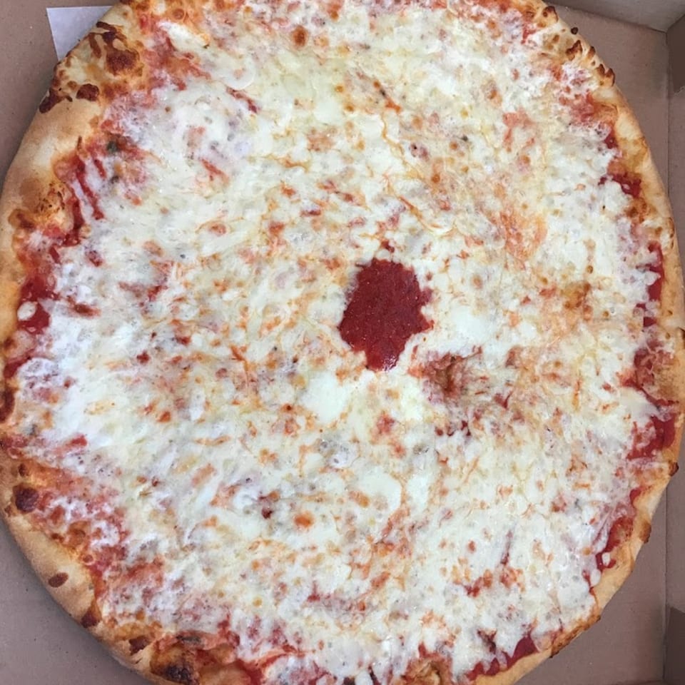 A large, round cheese pizza with a small dollop of red sauce in the center.